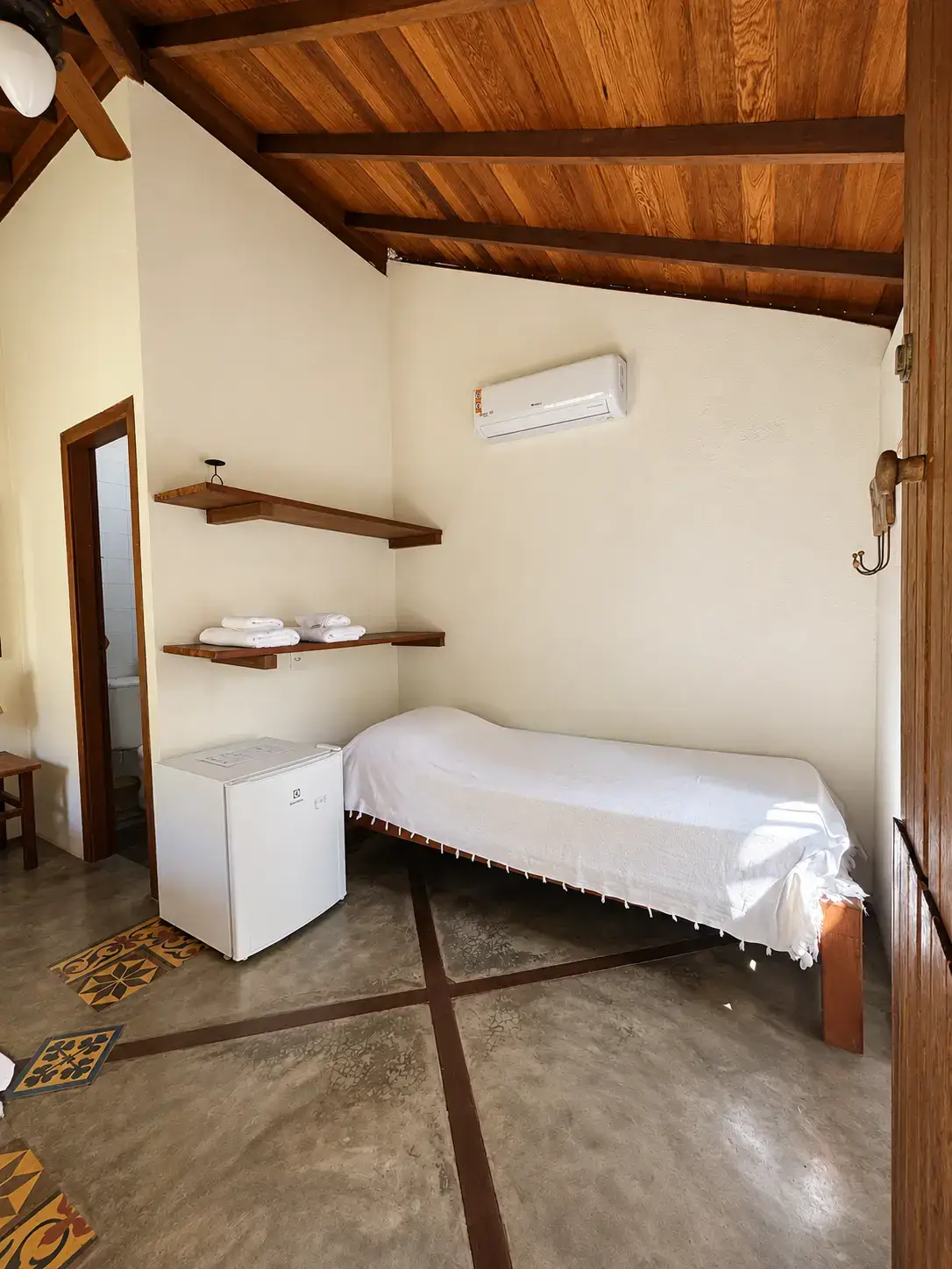 Quarto do Bangalô 7 com cama de casal, madeira aparente e iluminação acolhedora