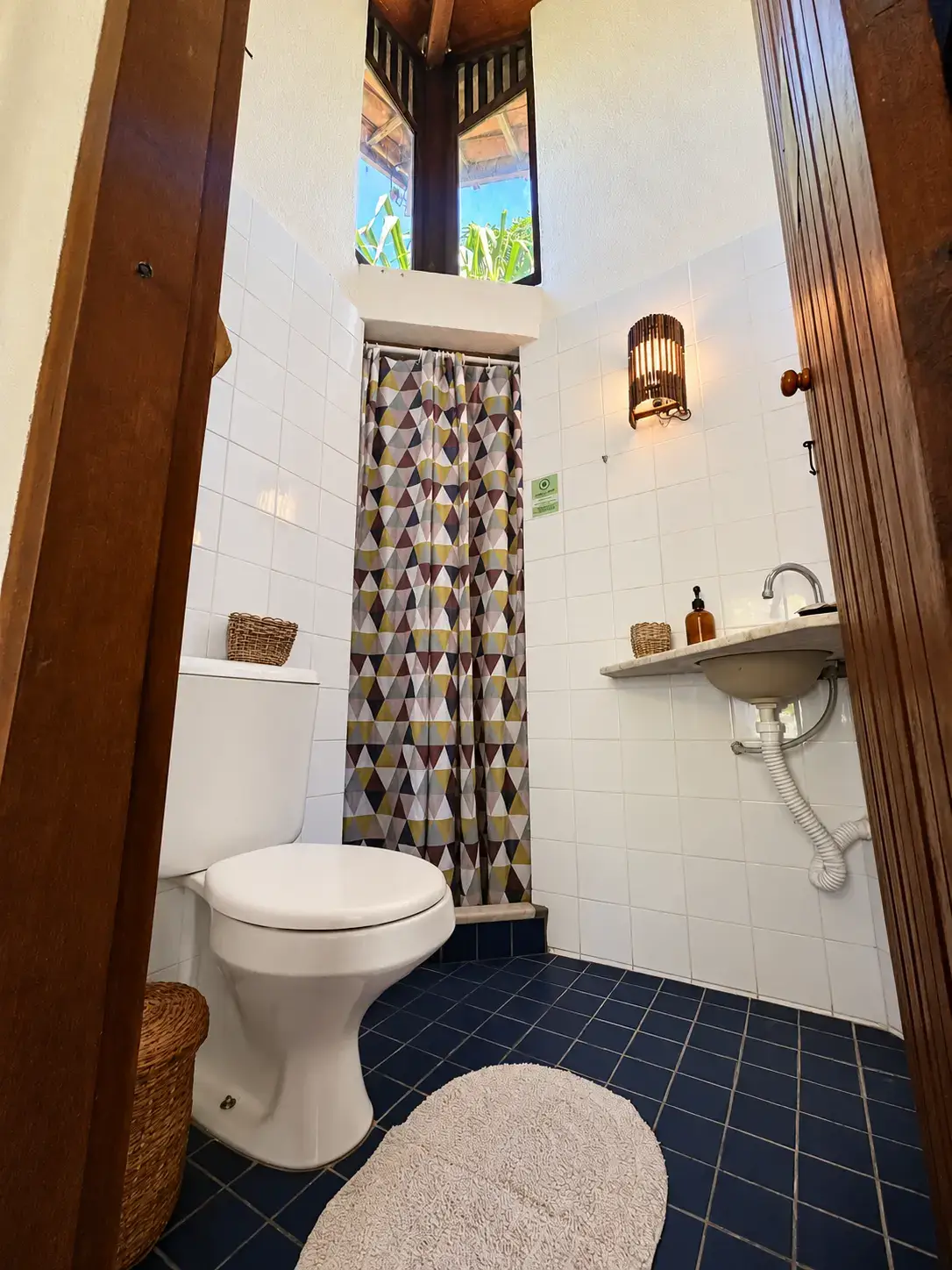 Banheiro do Bangalô 7 com azulejos escuros e luz natural