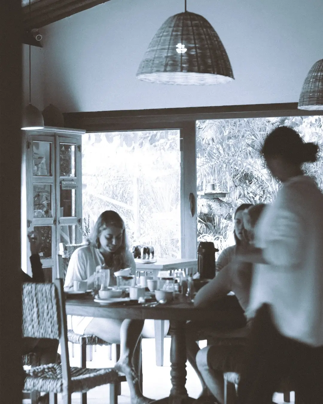 Registro em preto e branco de pessoas reunidas à mesa do café da manhã na Pousada Terra