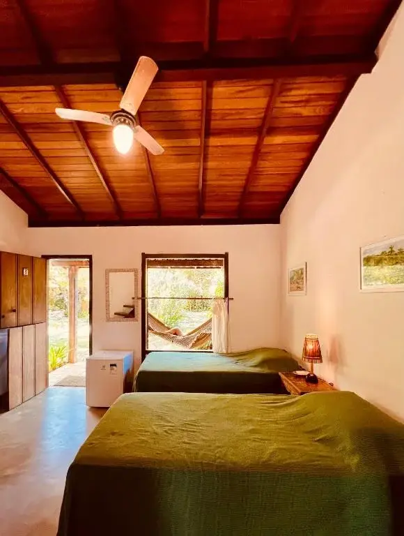 Ambiente da suíte com camas e vista para a varanda