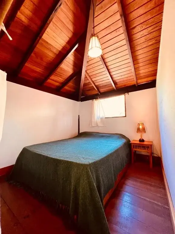 Cama no nível superior sob teto de madeira