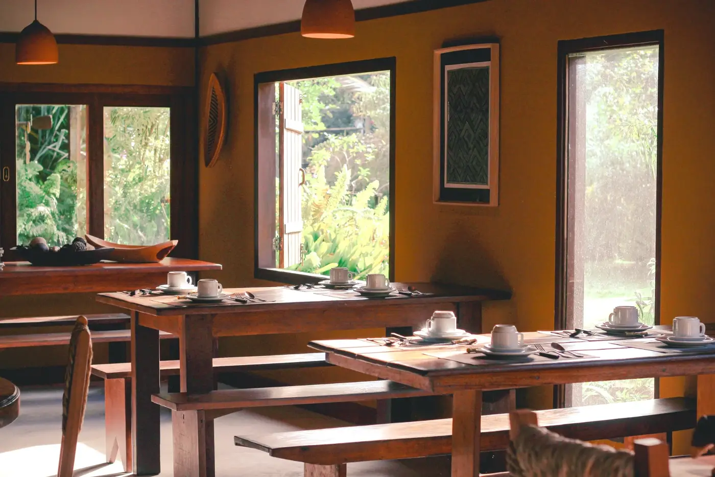 Salão do café da manhã da Pousada Terra, com mesas e janelas para o jardim
