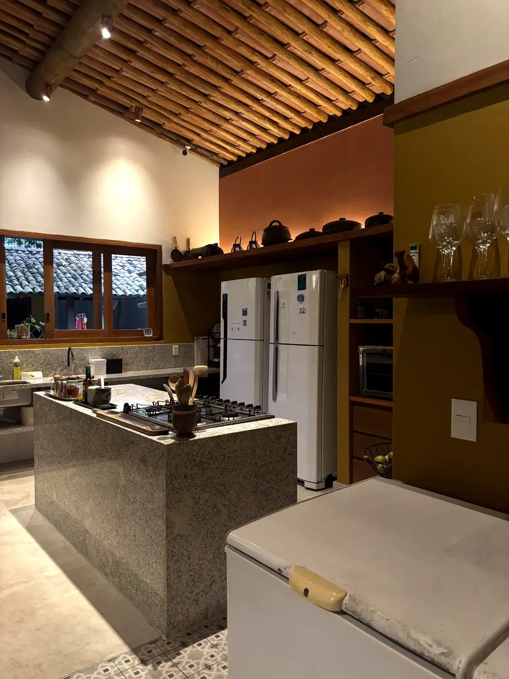 Cozinha com ilha central e teto de madeira